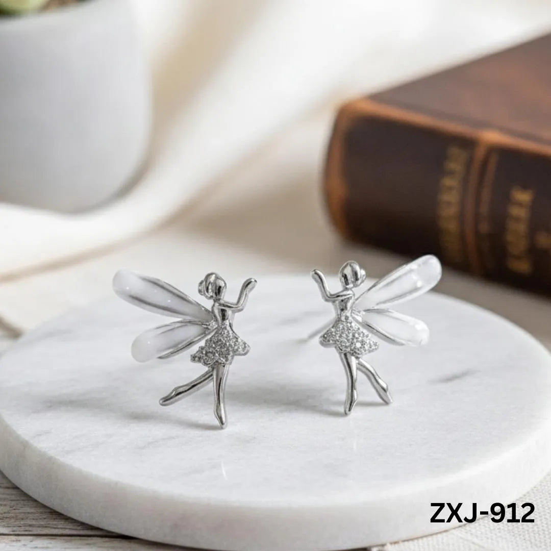 Silver fairy earrings on a marble surface with a blurred book in the background