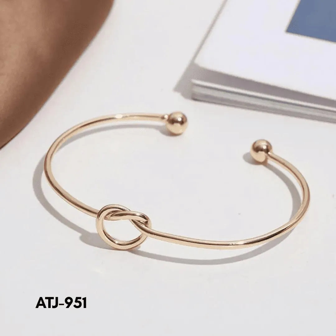 Rose gold bracelet with a knot design on a white surface, labeled ATJ-951.